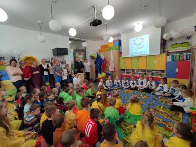 Występujące dzieci i widownia-przedszkolaki siedzace na dywanie i przy ścianie nauczyciele