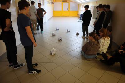 Uczniowie klasy szóstej sterują sześcioma robotami photon po korytarzu szkolnym.