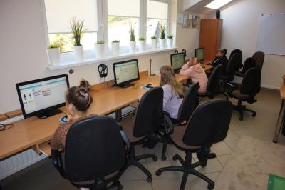Uczniowie siedzą przed komputerami. Na stronie code.org uczą się programowania przy pomocy tematycznych gier.