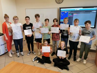 Uczniowie szkoły podstawowej pozują do zdjęcia grupowego trzymając w ręku certyfiakt uczestnictwa w codeweek 2022.