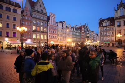 Uczniowie zwiedzają centrum Wrocławia. Spacer po rynku w wieczorowej porze.