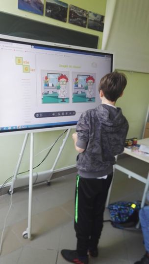 Uczeń obsługuje interaktywny program na monitorze dotykowym