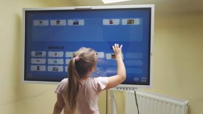 Dziewczynka korzysta z oprogramowanie multimedialnego na interaktywnym monitorze
