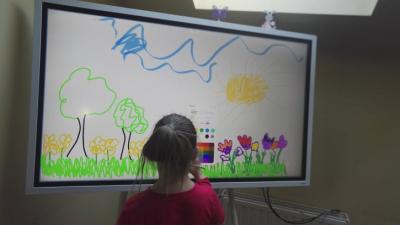 Dziewczynka rysuje rysunek na interaktywnym monitorze