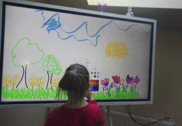 Dziewczynka rysuje rysunek na interaktywnym monitorze