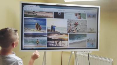 Na interaktywnym monitorze wyświetlają się miniatury zdjęć z wakacji.
