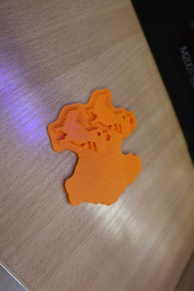 Wydruk modelu z drukarki 3D. Wydrukowane breloczki z pomarańczowego filamentu.