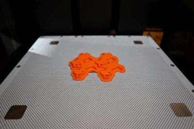 Wydruk modelu z drukarki 3D. Wydrukowane breloczki z pomarańczowego filamentu.
