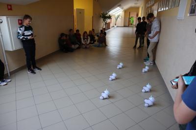 Uczniowie klasy szóstej sterują sześcioma robotami photon po korytarzu szkolnym.