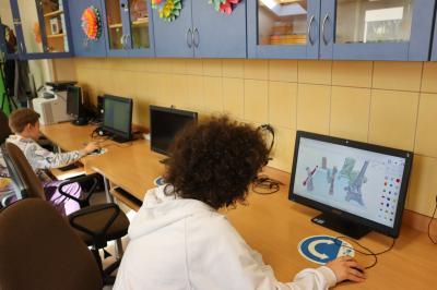 Uczeń wykonuje na platformie Tinkercad ćwiczenia z modelowania 3D. Na ekranie monitora widać budowle oraz rzeźby 3d.