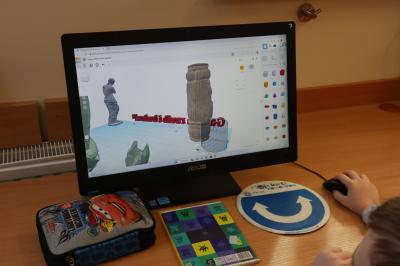 Uczeń wykonuje na platformie Tinkercad ćwiczenia z modelowania 3D. Na ekranie monitora widać budowle oraz rzeźby 3d.