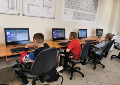 Uczniowie siedzą przy komputerach i poprzez stronę code.org kodują gry