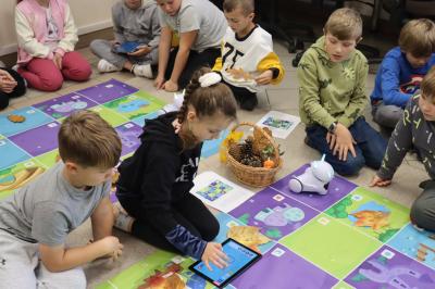 Uczniowie programują robota Photon aby pokonał jesienną trasę na macie edukacyjnej.