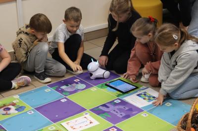 Uczniowie programują robota Photon aby pokonał jesienną trasę na macie edukacyjnej.