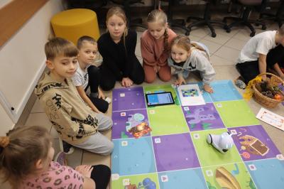 Uczniowie programują robota Photon aby pokonał jesienną trasę na macie edukacyjnej.