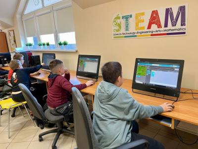 chłopcy siedzą przed komputerami w trakcie zajęć z kodowania.