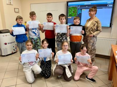 młodsi uczniowie stoją trzymając w dłoniach certyfikaty