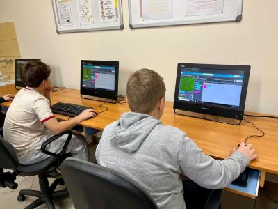 chłopcy siedzą przed komputerami w trakcie zajęć z kodowania gry.